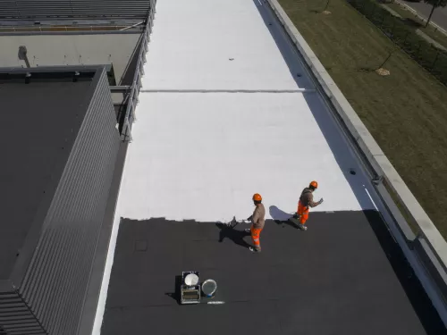 Application de peinture blanche Axiroof sur un toit de bâtiment